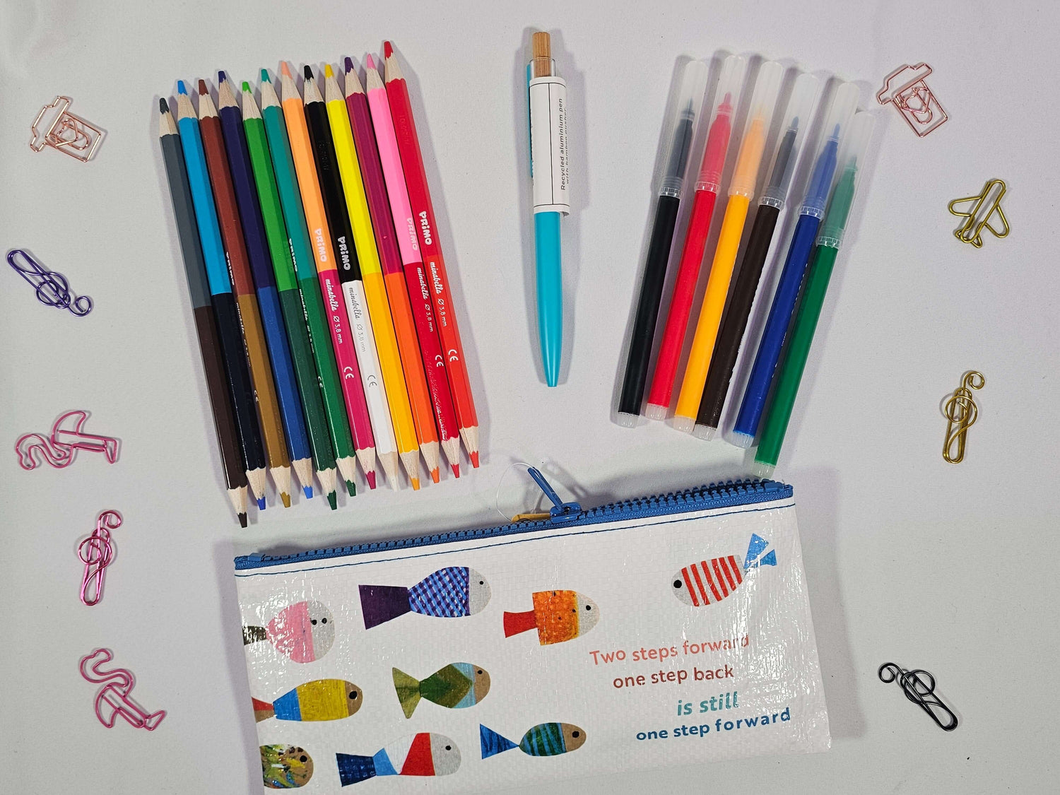 Colorful pencils and pens arranged with a fish-patterned pouch, perfect for art and stationery lovers.