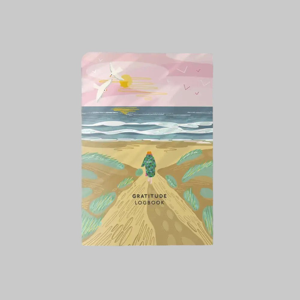 Illustration of a gratitude logbook on a sandy beach, featuring waves, a sunset, and a figure walking.