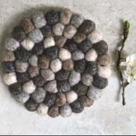 Pom pom coaster with a branch and flowers on a light background