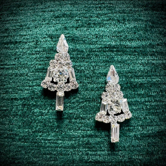 Pair of crystal tree-shaped earrings on a green textured background