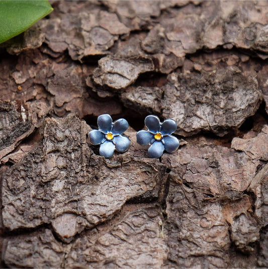 Blue flower-shaped earrings on a textured brown surface