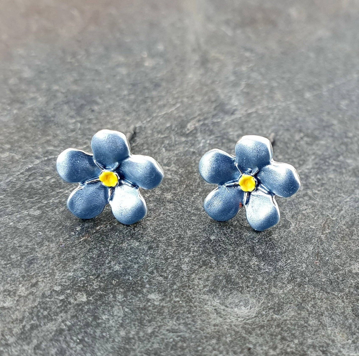 Blue flower-shaped earrings on a gray surface