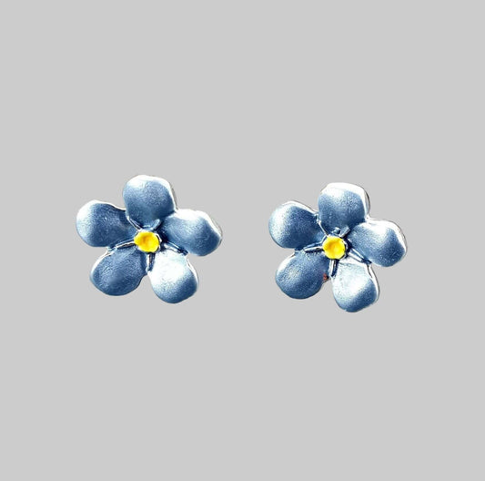 Blue flower-shaped earrings on a gray surface