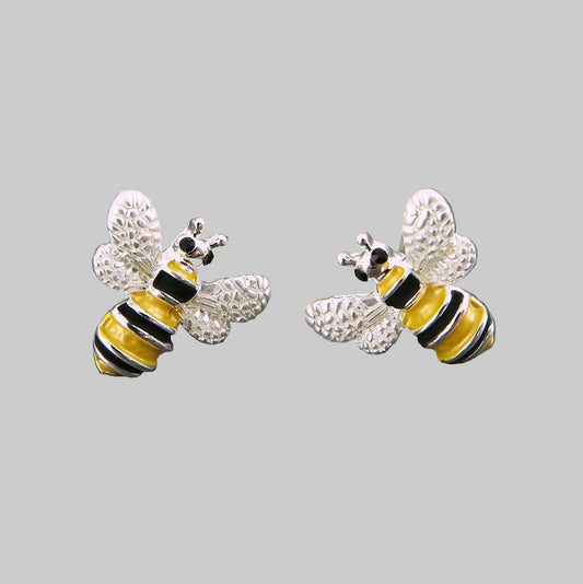 Bee-shaped earrings on a gray stone surface