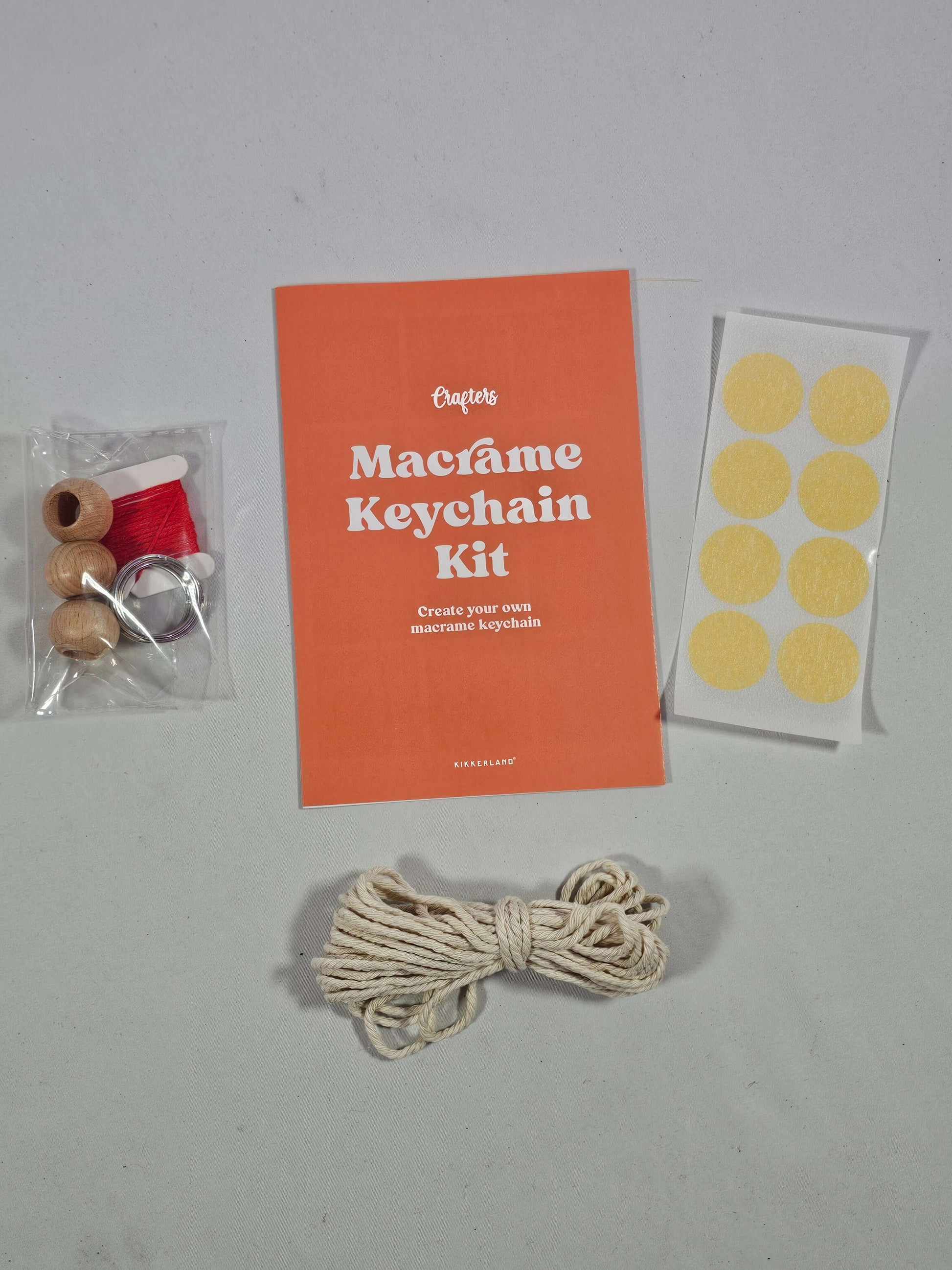 Macrame keyring kit from Kikkerland with cotton cord, wooden beads, red cord, and masking tape dots for creative DIY keyrings.