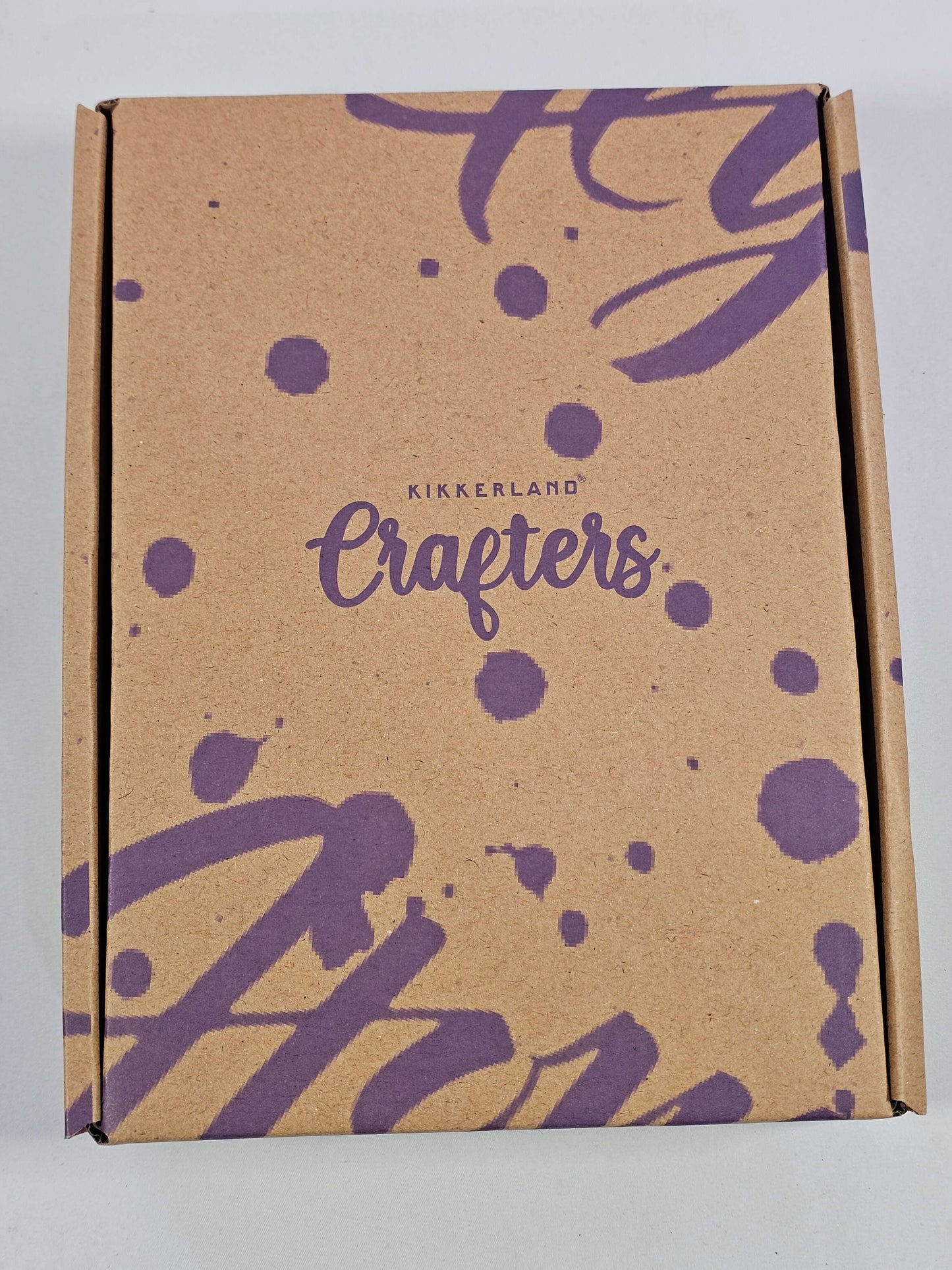 Kikkerland brush lettering kit packaging featuring a kraft box design with purple splatters and the word 'Crafters'.