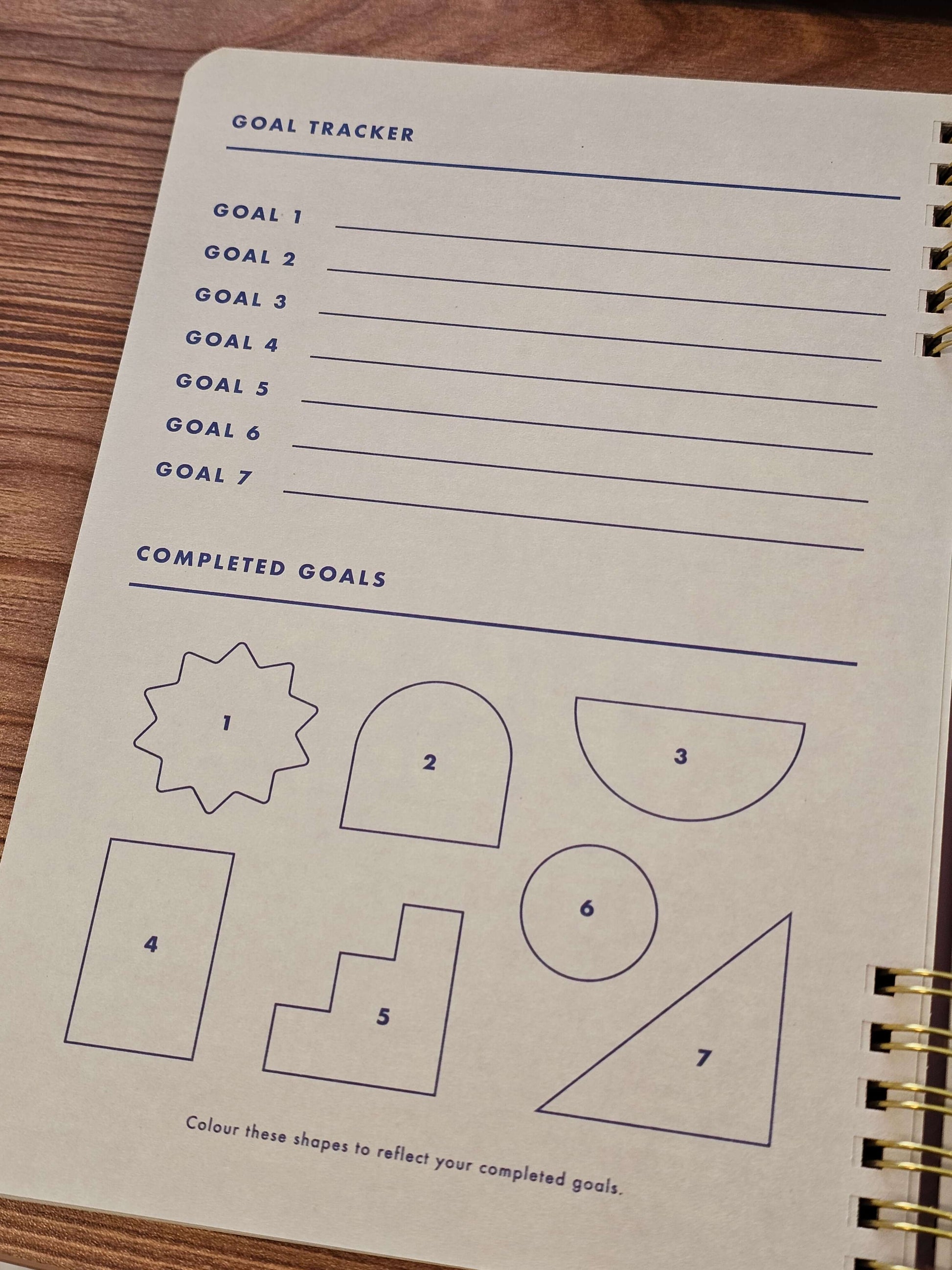 Goal tracker page in colorful Habits & Goals Tracker notebook with outlined shapes for marking completed goals.