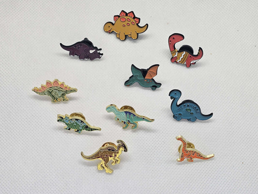 Collection of cute dinosaur enamel pin badges in various designs, perfect for bags and clothing accessories.