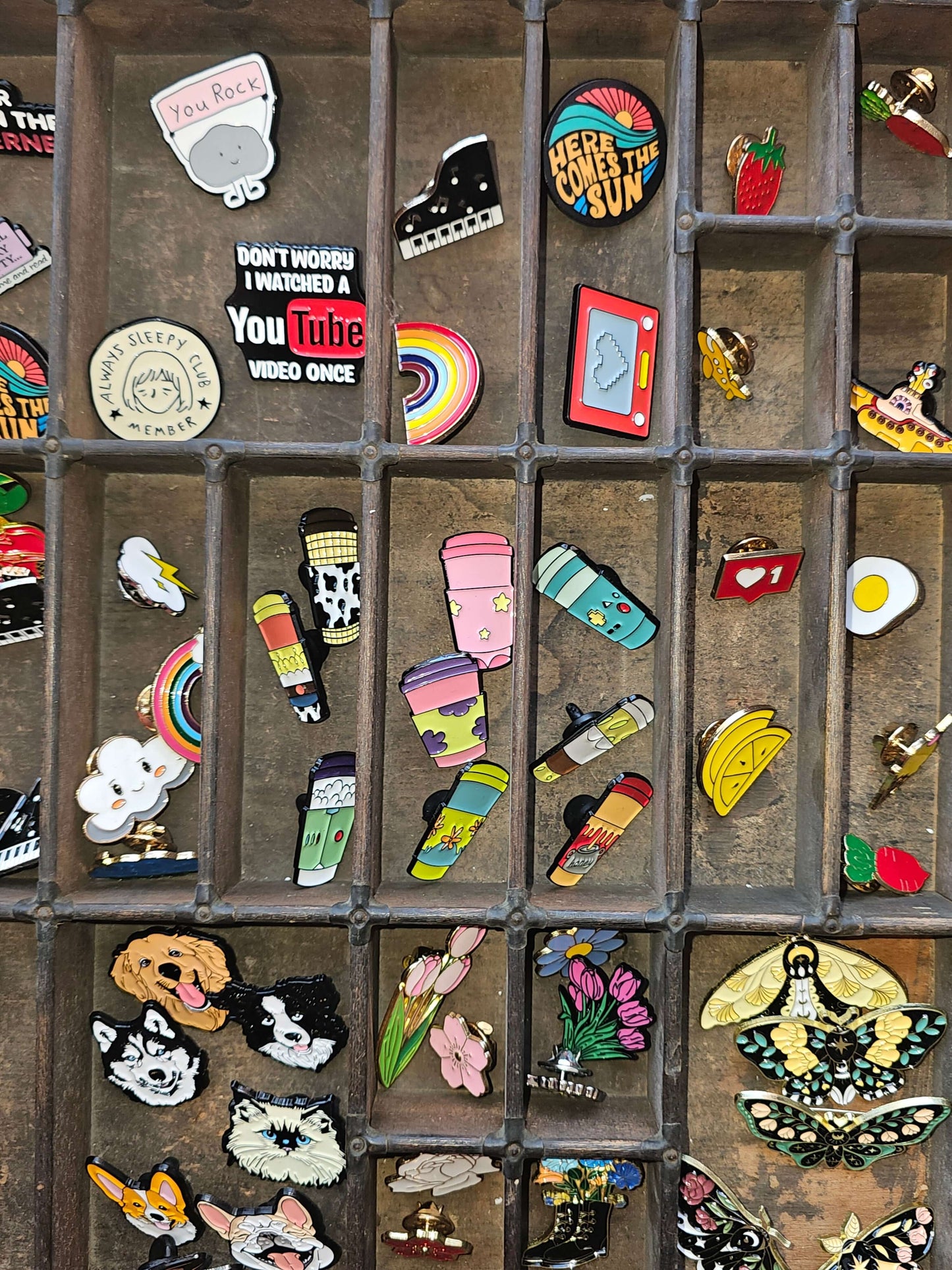 Colorful collection of mystery pin badges arranged in a display tray, showcasing unique designs and styles.