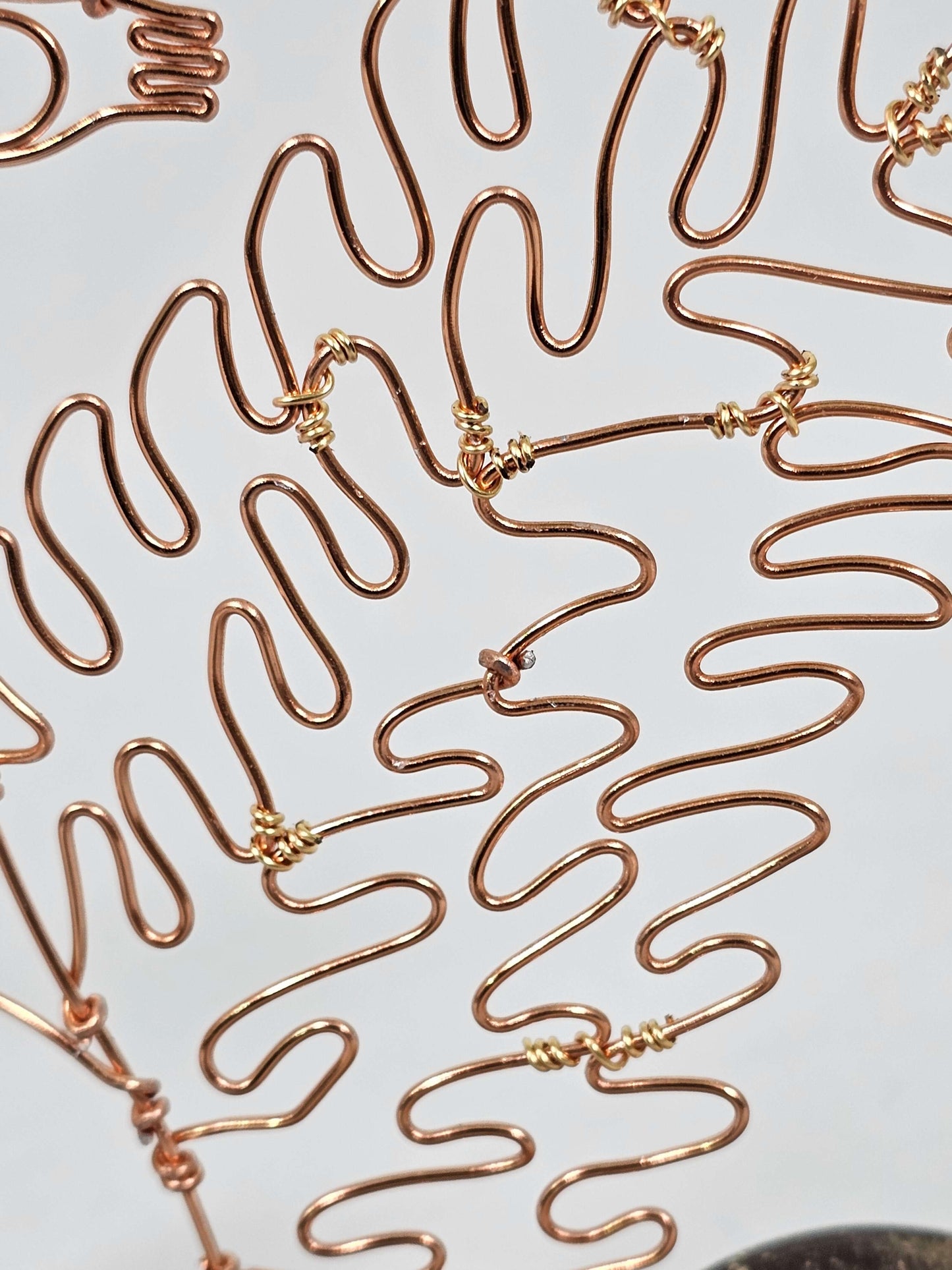 Close-up of gold wire sculptures on a white background