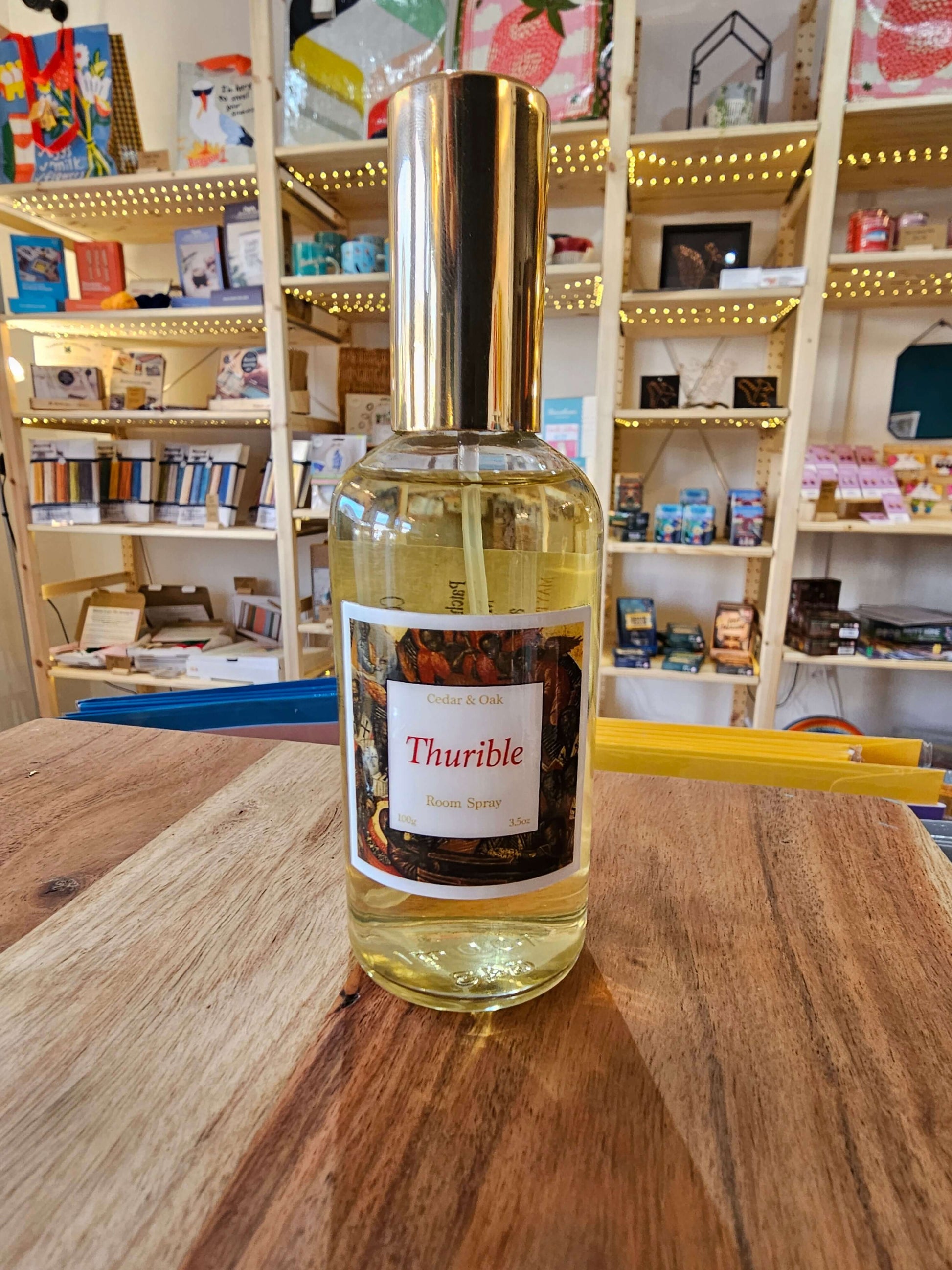 Bottle of Thurible room spray on a wooden surface with a bookshelf in the background