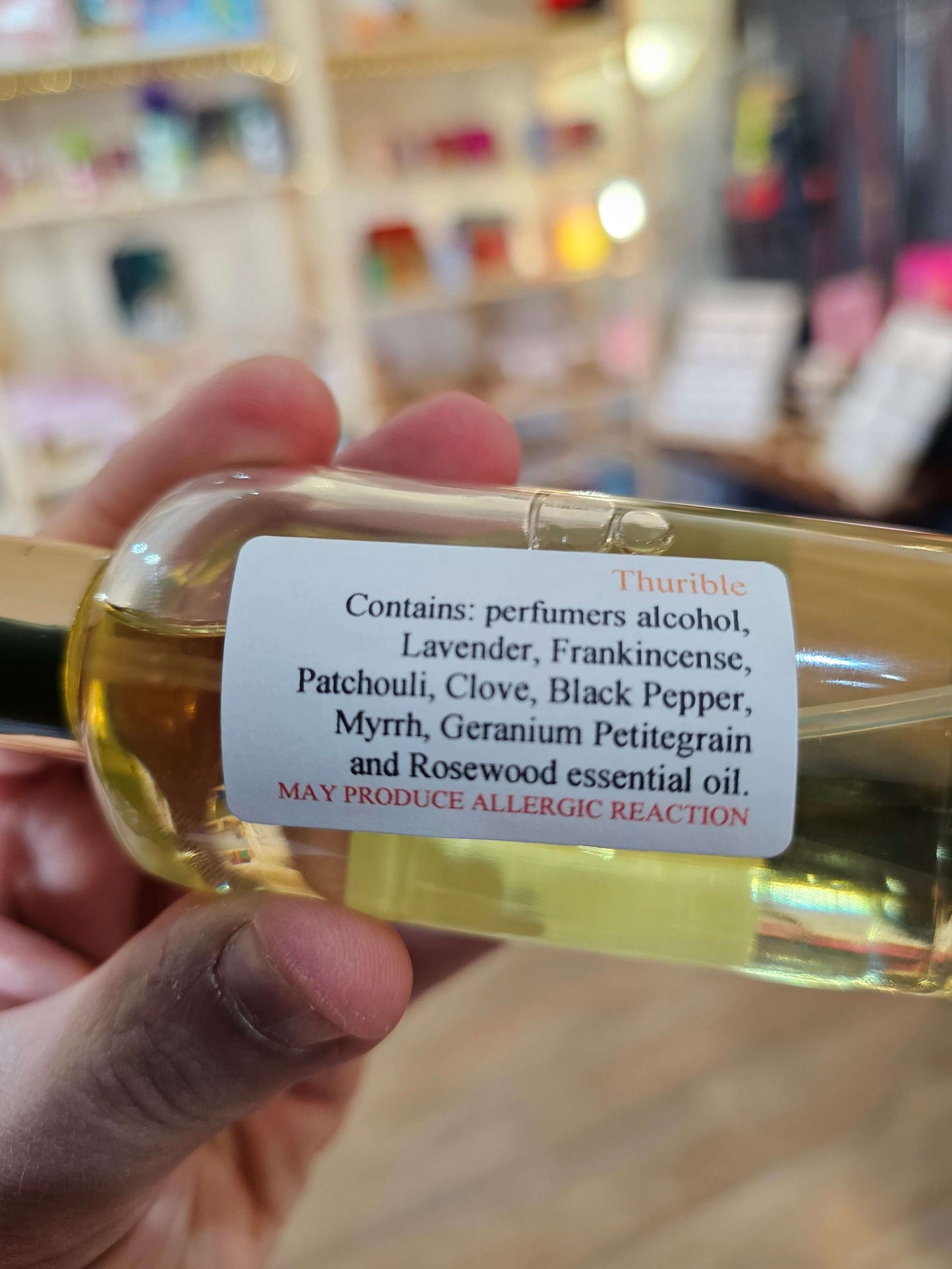 Hand holding a bottle of room spray with a blurred background