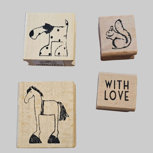Four wooden stamps with animal illustrations and 'WITH LOVE' text on a wooden surface