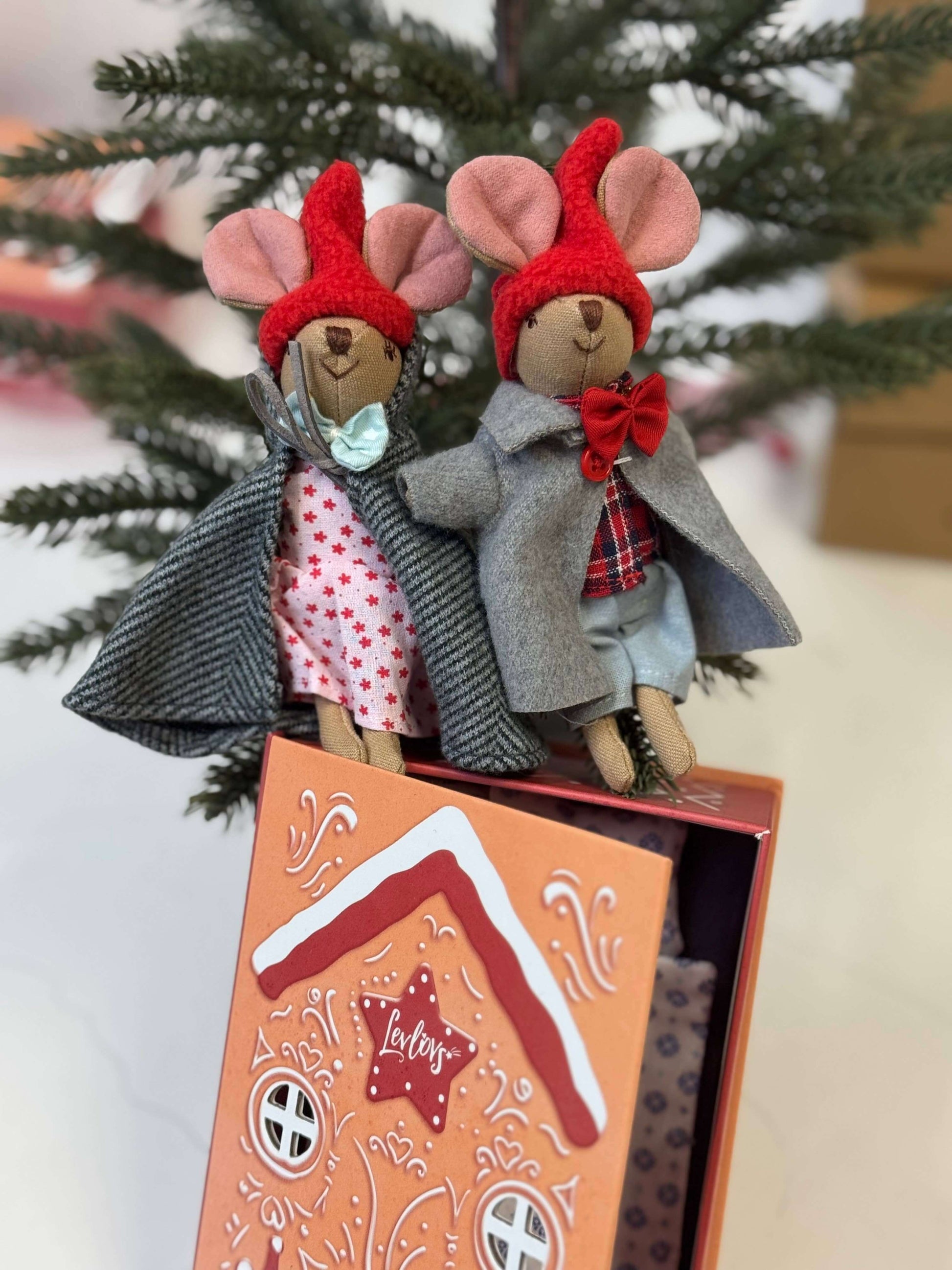 Two toy mice in outfits with a decorative box on a tree branch background