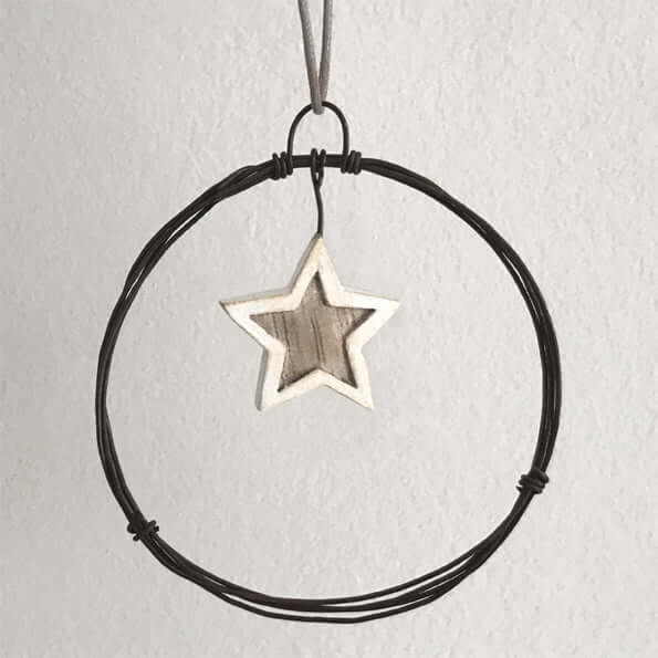 Star-shaped pendant on a black cord against a light gray background