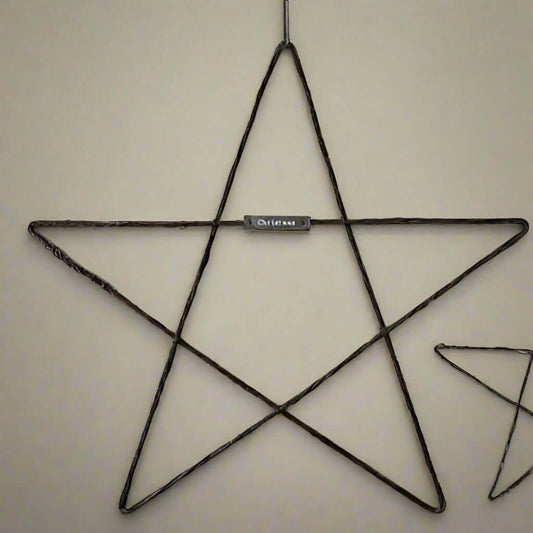 Large Metal Hanging Christmas Star - East of India on a wall, showcasing rustic handmade design with a silver plaque.