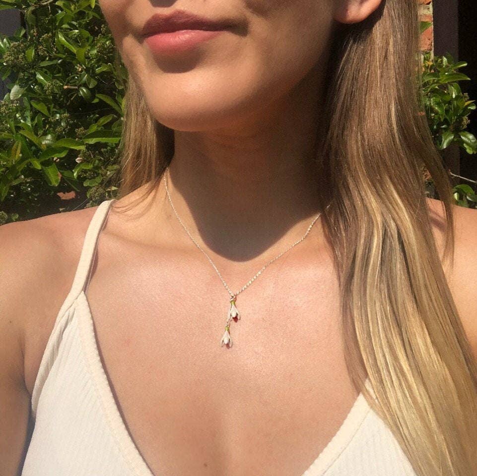 Close-up of a woman wearing a necklace with a pendant outdoors