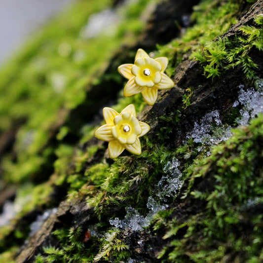 Yellow flower-shaped earrings on a mossy surface