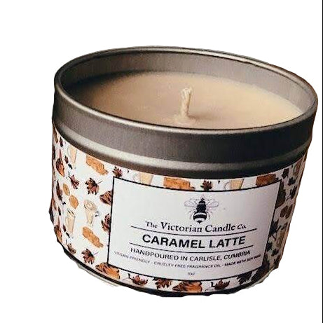 Caramel latte candle next to a glass of caramel latte on a wooden surface