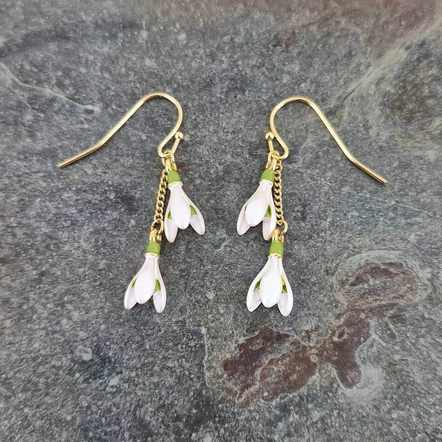 Pair of floral earrings with gold hooks on a stone surface