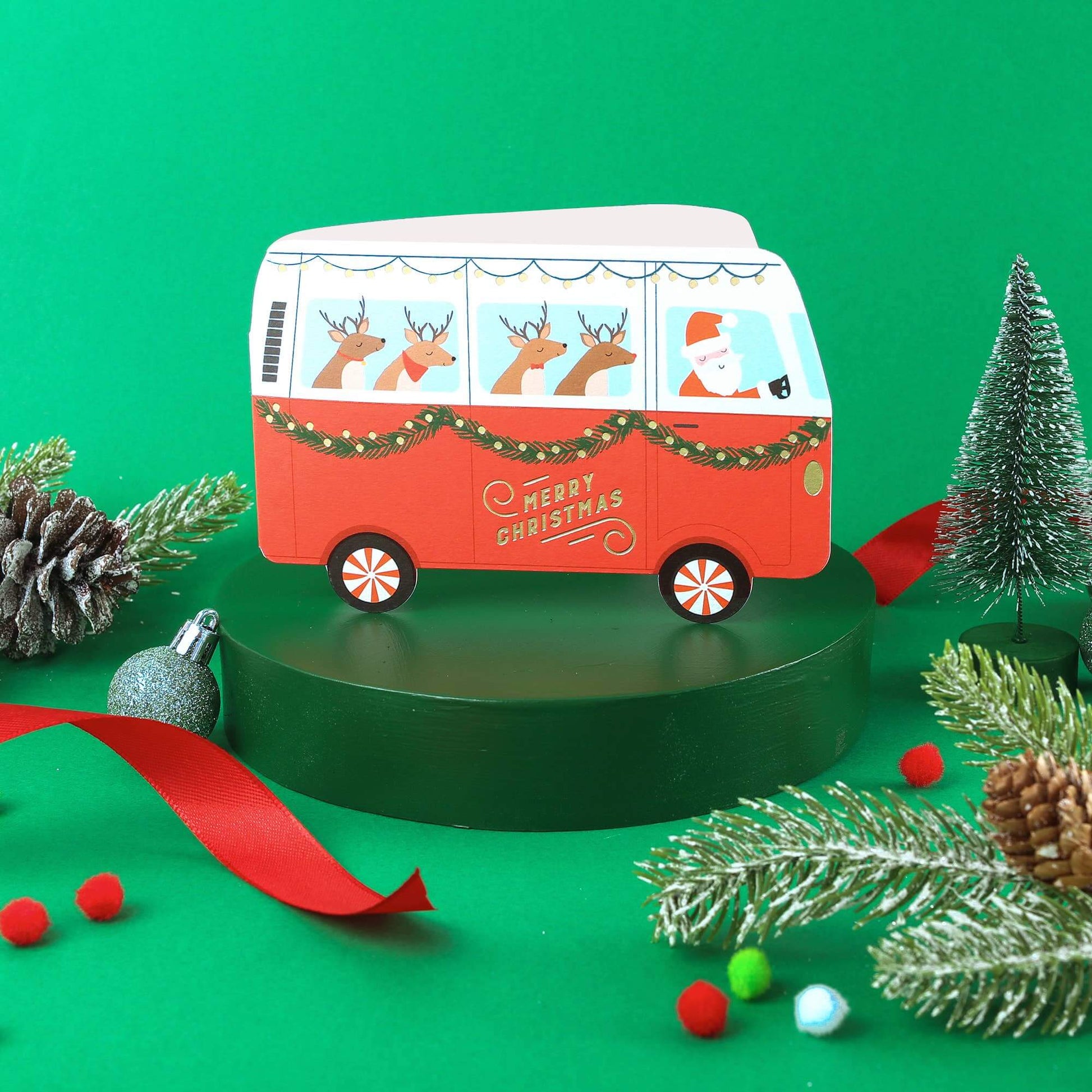 Red Christmas-themed van with Santa Claus and reindeer on a green background
