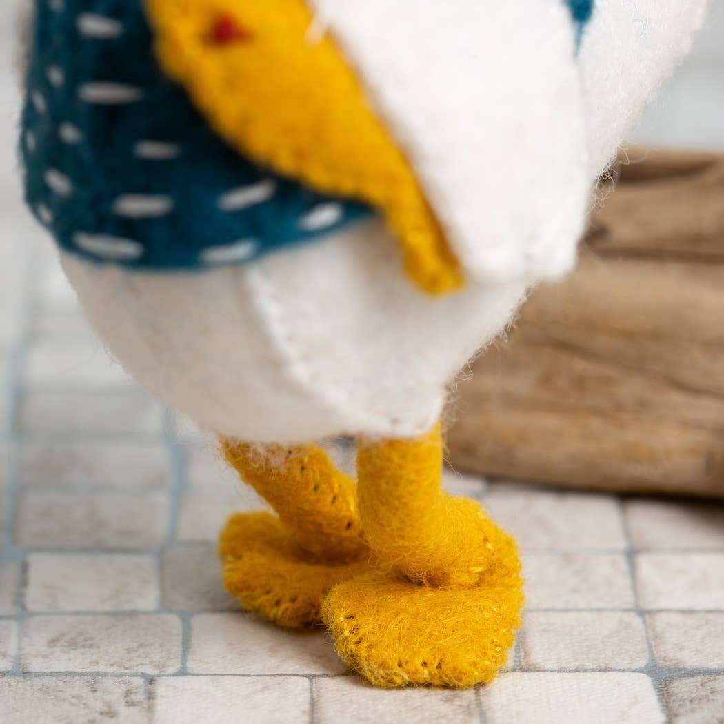 Close-up of a toy goose with yellow feet on a tiled floor