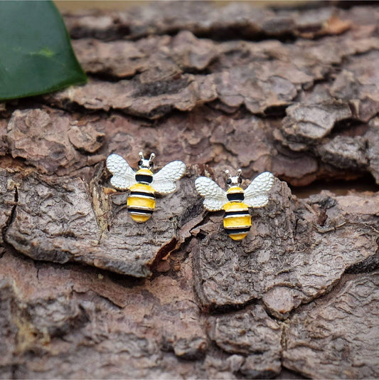 Bee-shaped earrings on a textured wooden surface
