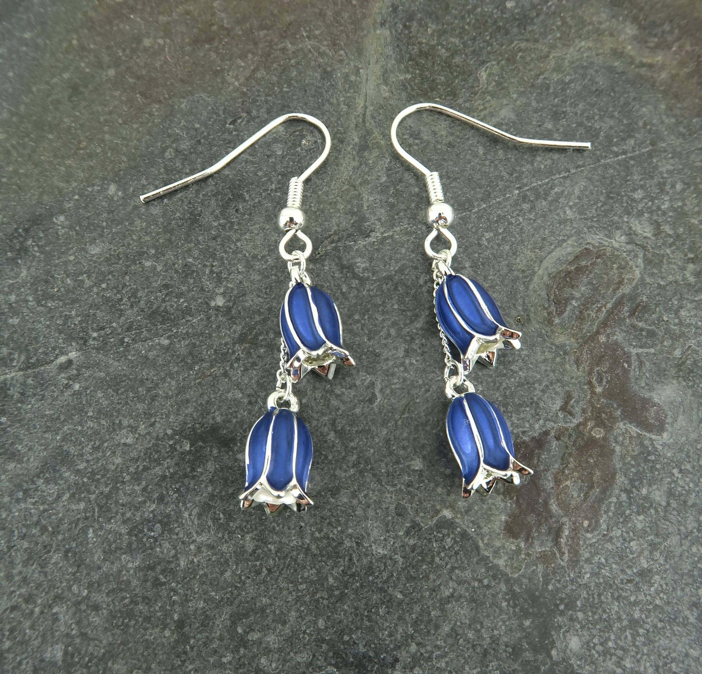 Pair of bluebell-shaped earrings on a dark stone background