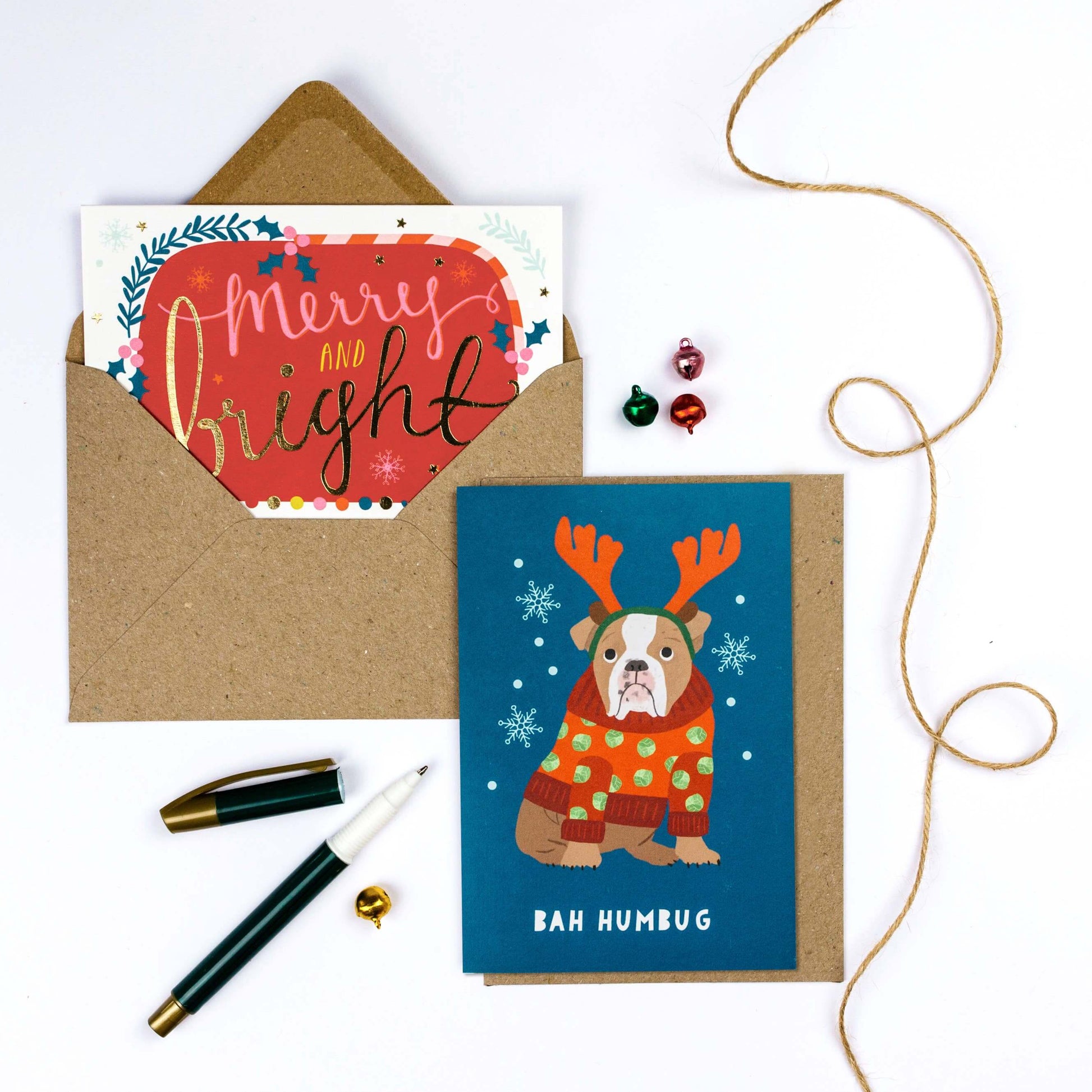 Two Christmas cards with envelopes and decorative items on a white background