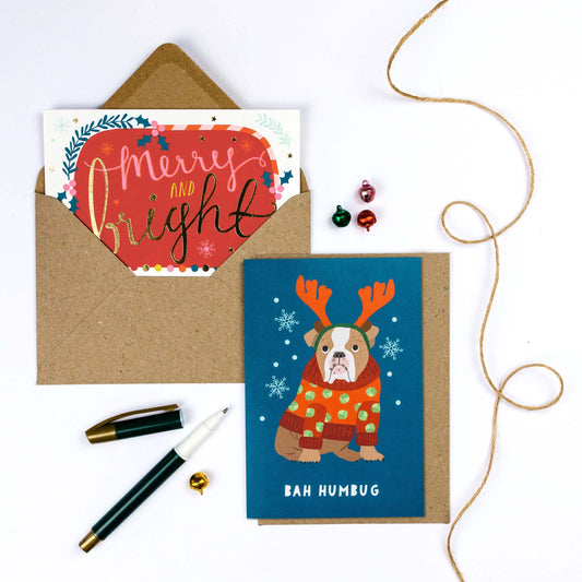 Two Christmas cards with envelopes and decorative items on a white background