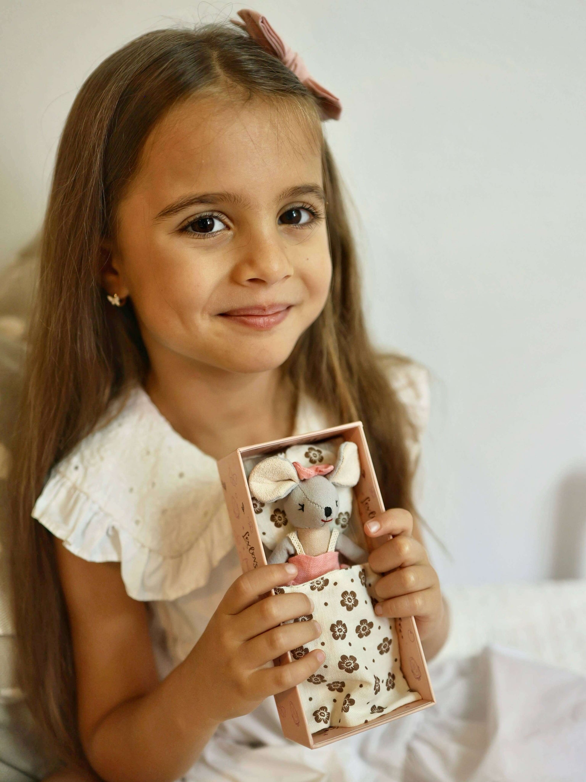 Young girl holding a small box with a toy inside against a plain background
