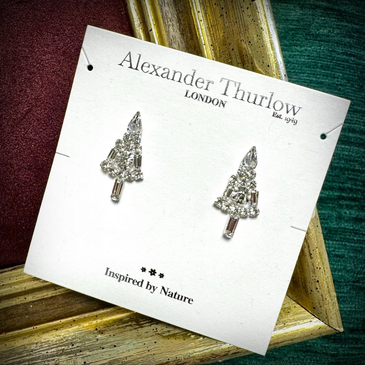 Tree-shaped earrings on a 'Alexander Thurlow London' card with a nature theme.