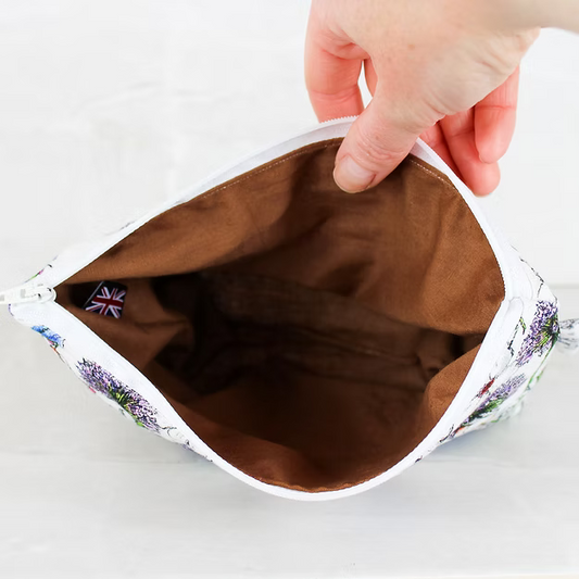 Hand opening a small pouch with floral edge on a white background