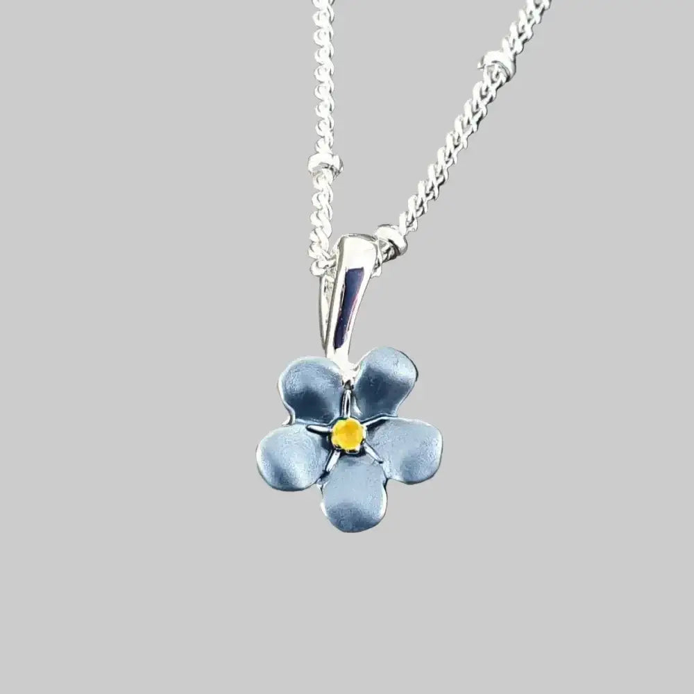 Silver necklace with a blue flower pendant on a gray stone background