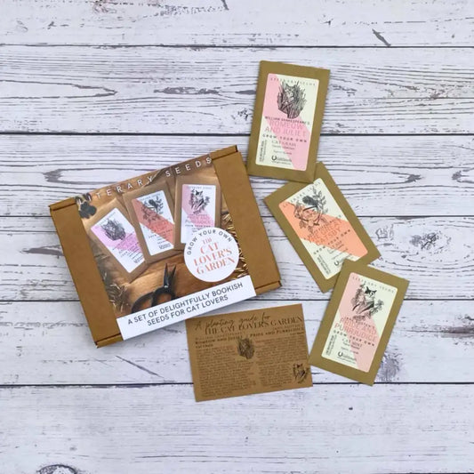 Literary Seeds: The Cat Lover's Garden seed packets displayed on a wooden surface, perfect for cat lovers and book enthusiasts.