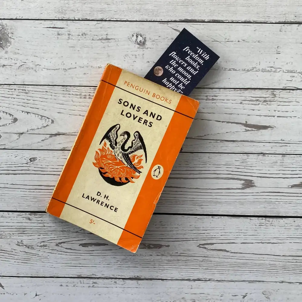 Oscar Wilde literary quote bookmark displayed with D.H. Lawrence's 'Sons and Lovers' book on a wooden surface.