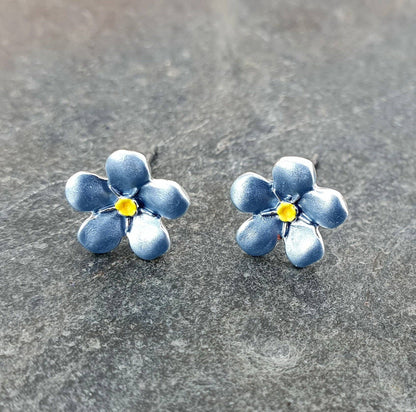 Blue flower-shaped earrings on a gray surface