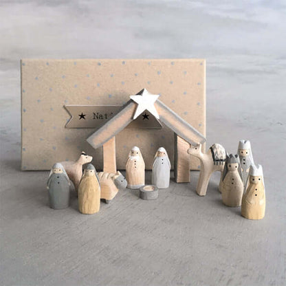 Wooden nativity set with stable and figures on a gray surface