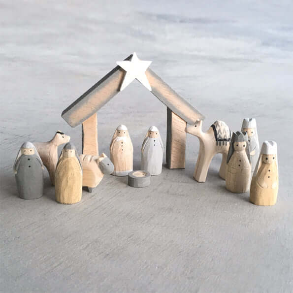 Wooden nativity set with stable and star on a light gray background