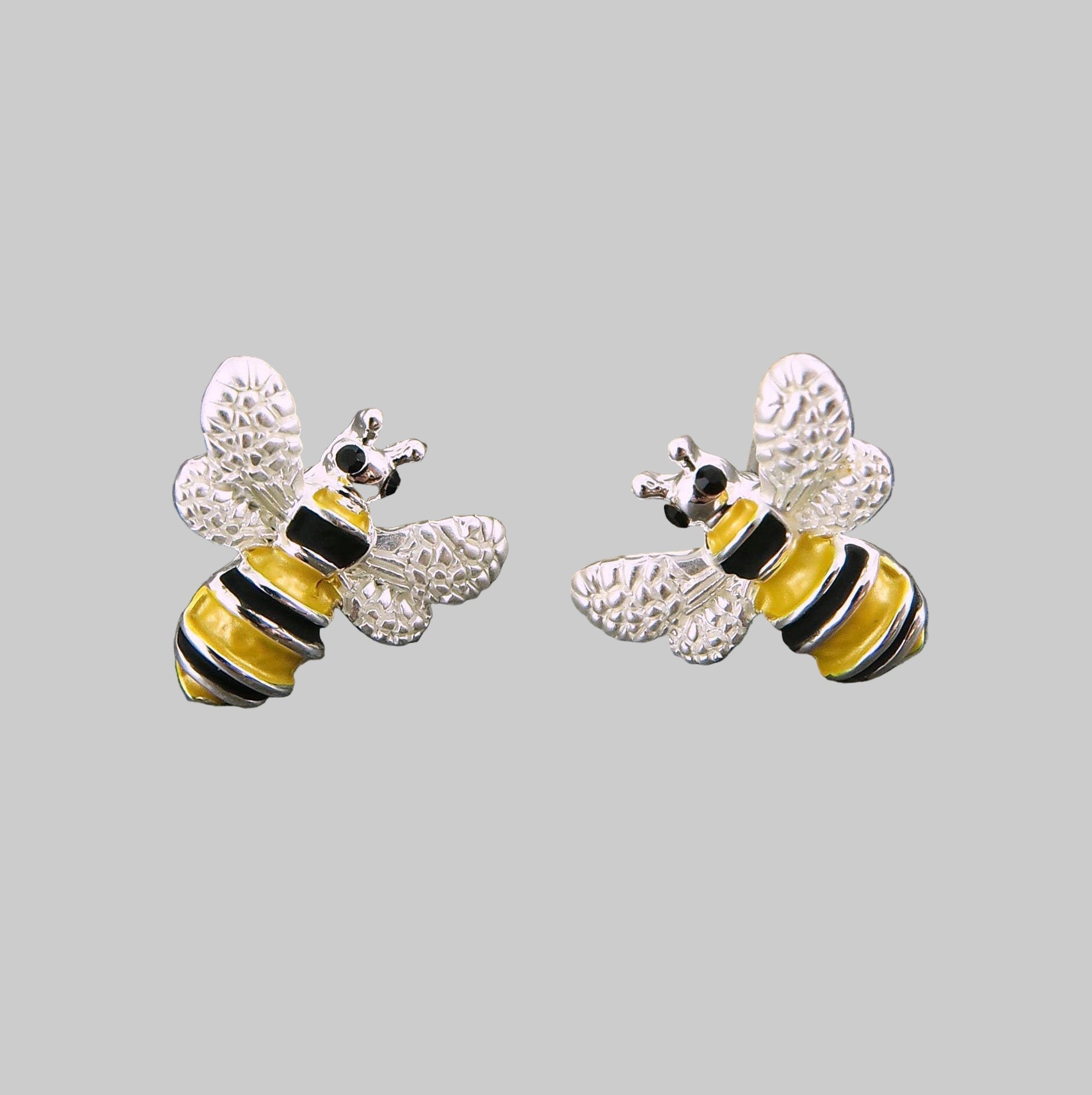 Bee-shaped earrings on a gray stone surface