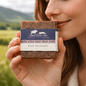 Person holding a bar of soap with 'Cragg House Farm' branding outdoors.