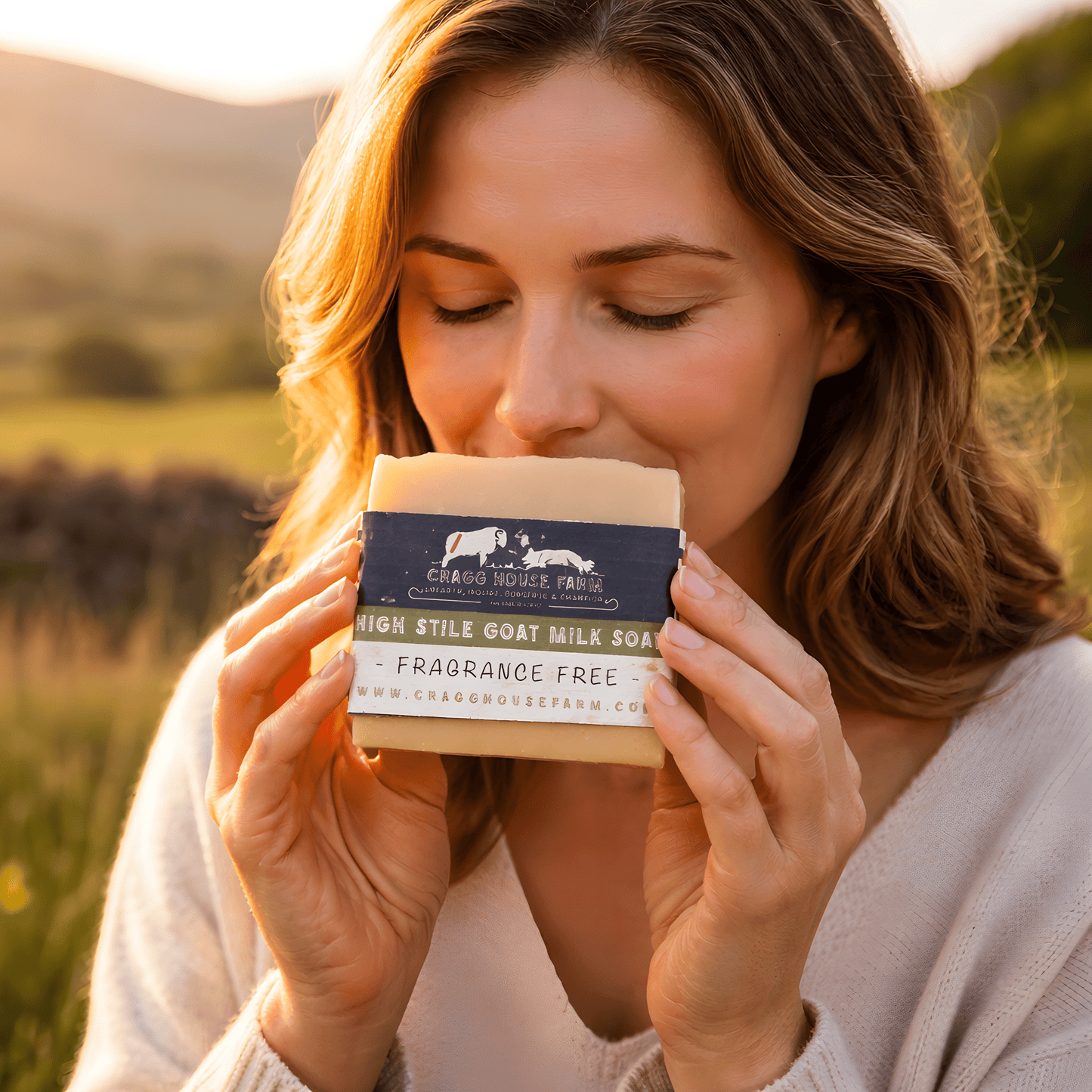 Person holding a bar of soap with 'Cragg House Farm' branding outdoors.