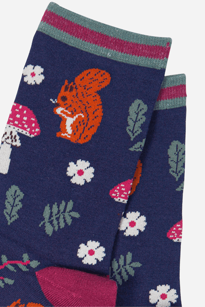 Navy blue sock with orange squirrel, pink mushrooms, and white flowers on a white background