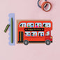 Red double-decker bus card with 'Happy Birthday' text on a pink background