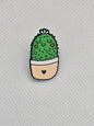 Cute cactus enamel pin badge with a smiling face in a pot, ideal for backpacks or jackets.