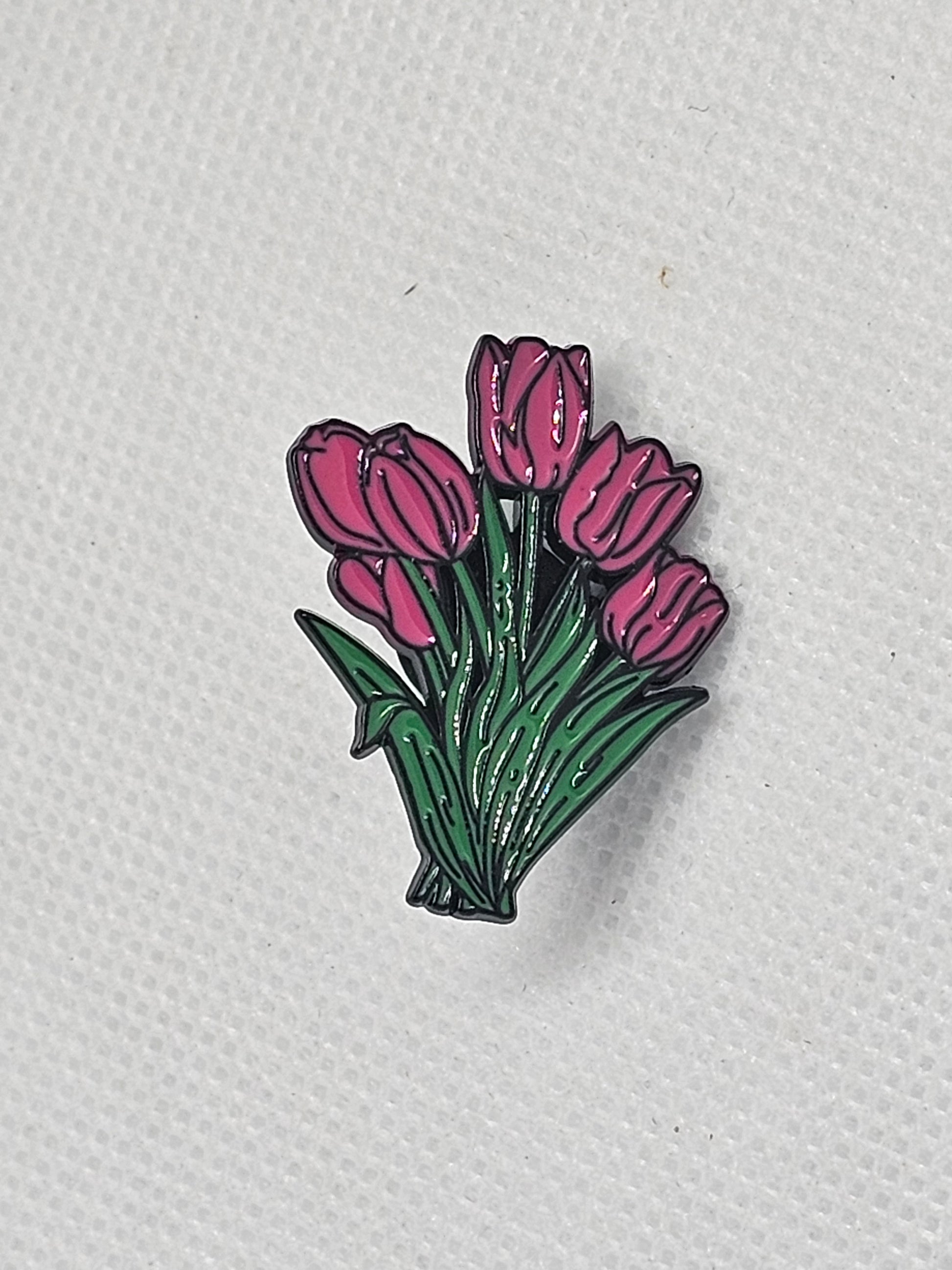 Colorful enamel pin badge featuring a bouquet of pink tulips on green leaves.