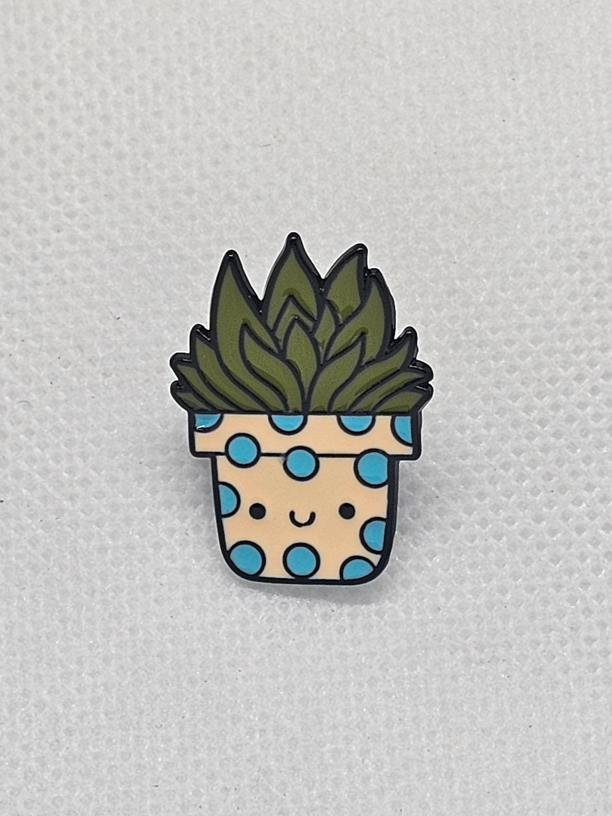 Quirky floral pin badge featuring a smiling plant in a polka-dotted pot, perfect for backpacks and jackets.