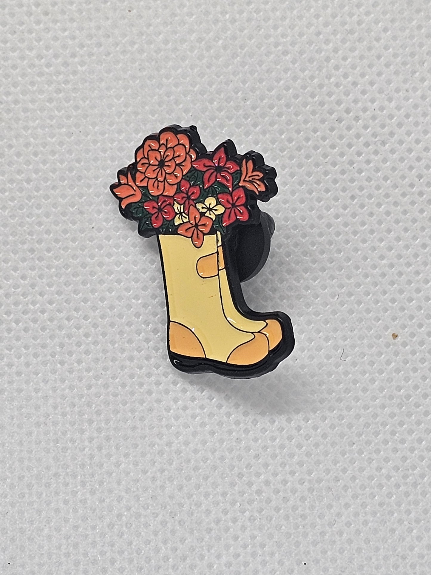 Enamel pin badge featuring a yellow boot filled with colorful flowers, perfect for plant lovers.