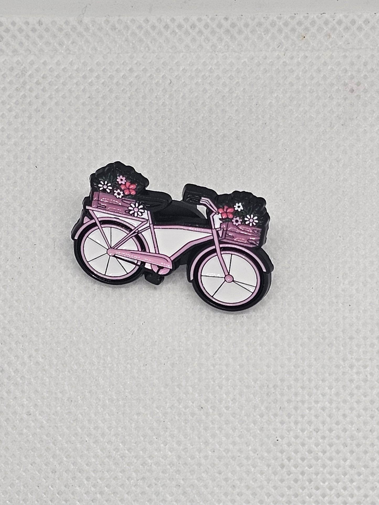Enamel pin badge of a pink bicycle with flower baskets, perfect for plant lovers and collectors.