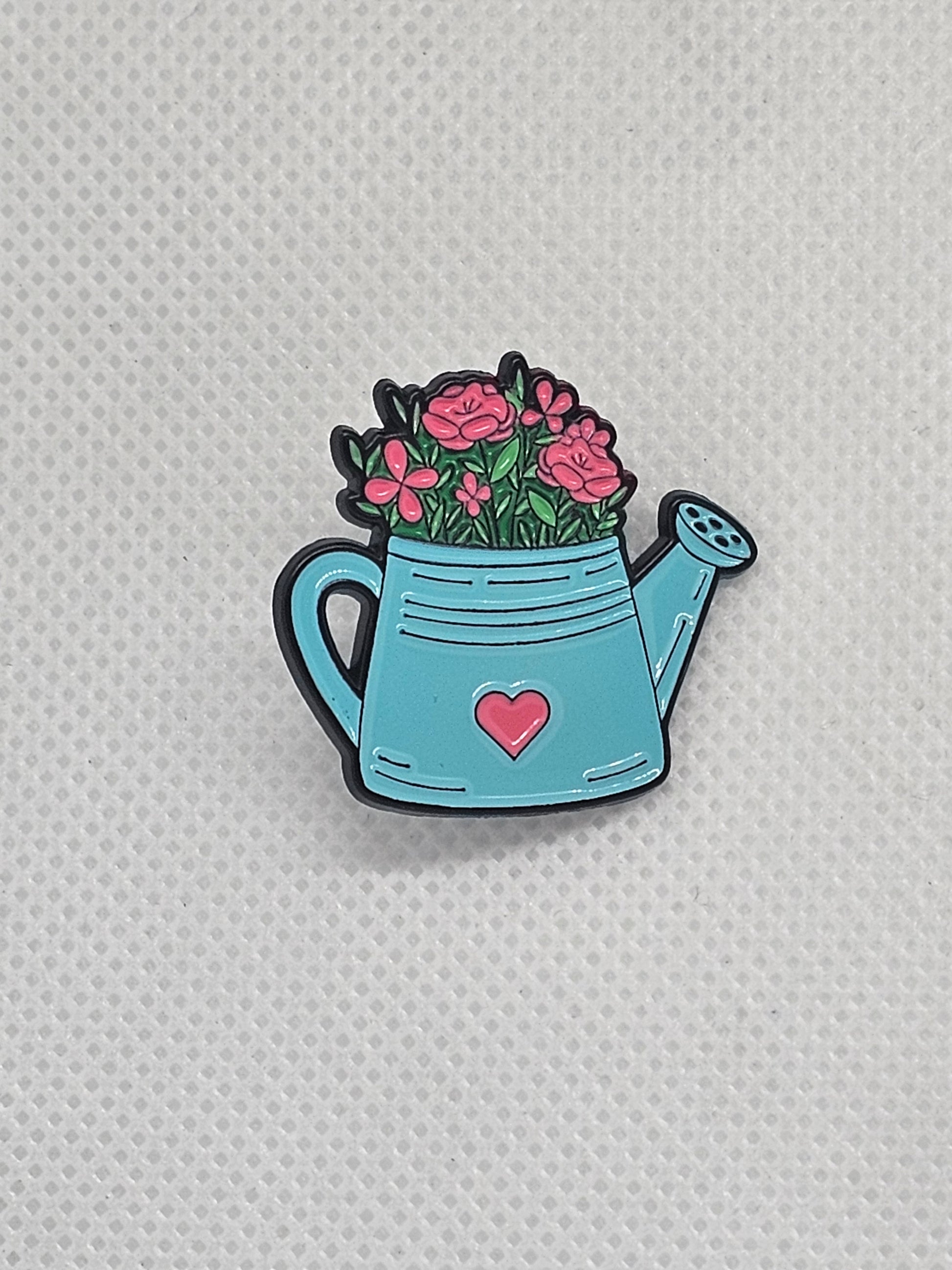 Cute watering can pin badge with pink flowers, perfect for plant lovers and gardening enthusiasts.